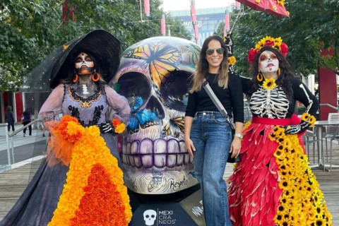 Mariana Cano posing with people wearing Day of The Dead costumes.