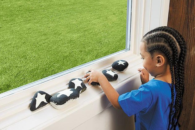 A child setting a painted rock on a windowsill