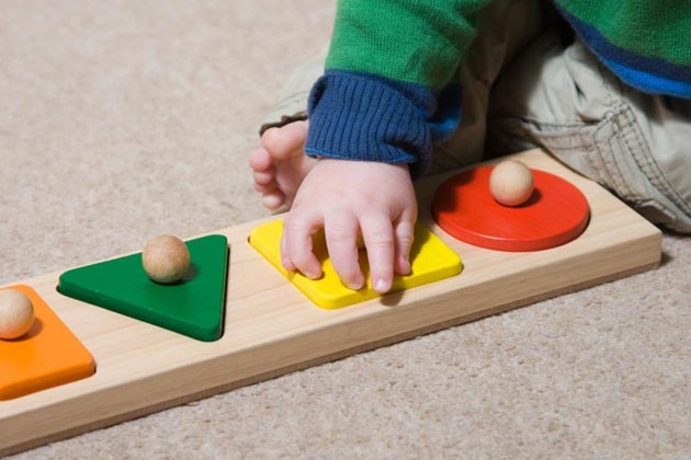A baby playing with a shape-sorter toy.
