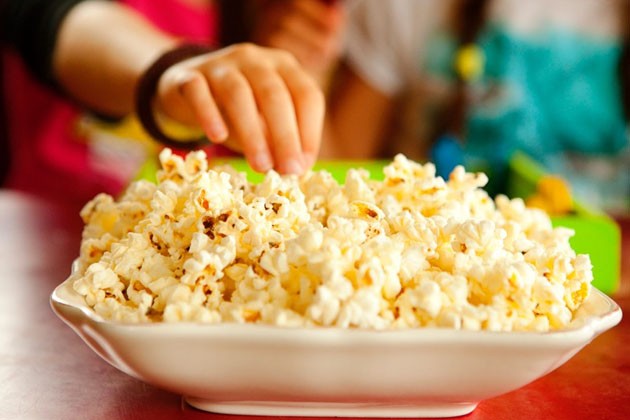 A hand reaching into a bowl of fluffy popcorn