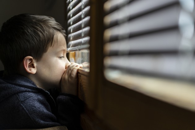 A young child staring out a window.