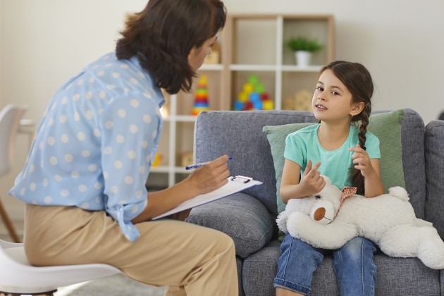 A counselor talking with a child holding a toy bear.