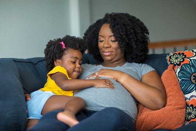 An expectant mother cuddling her toddler.