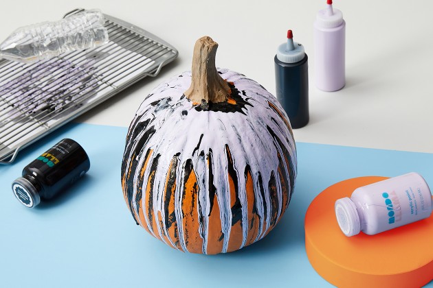 Uncarved pumpkin with black and white paint streaks.