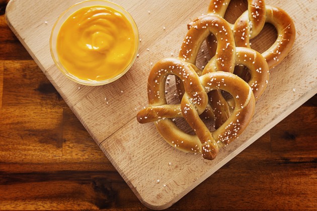 Three soft pretzels and a bowl of mustard dip.