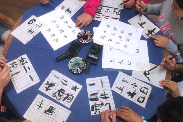 People trying writing Chinese characters with traditional ink and brushes.