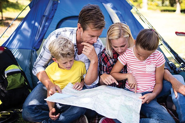A family in front of a tent reading a map.