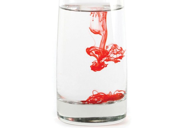 A glass of water with coloring beginning to swirl in it.