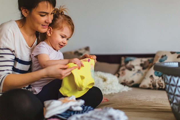 A mom shows her toddler how to fold clothes