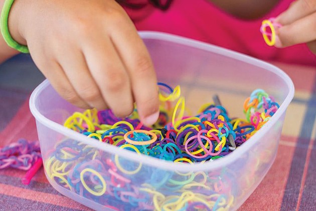 Image of child’s hands in a bowl of colorful mini-rubber bands.