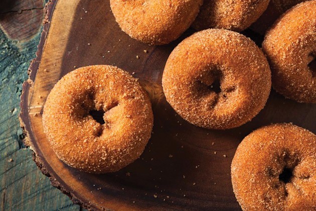 Freshly baked cinnamon doughnuts on a kitchen counter.