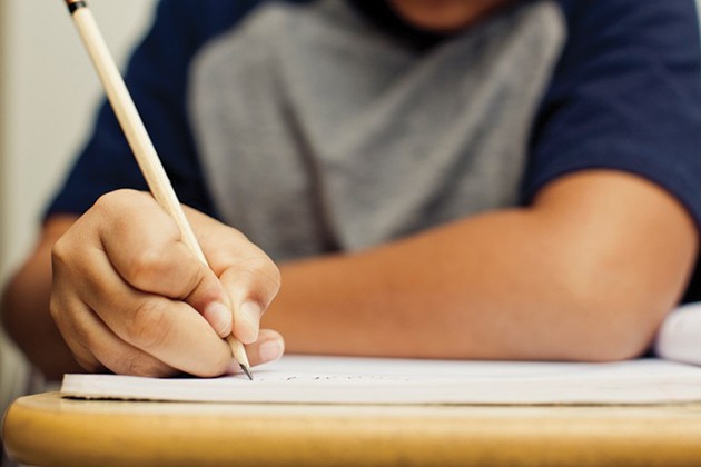 Child gripping a pencil and writing in a notebook.