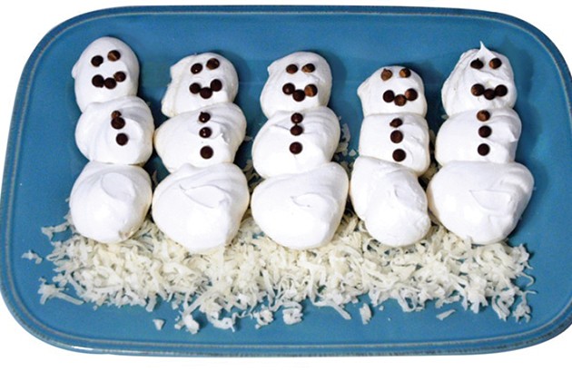 Meringue snowmen lined up on a plate. 