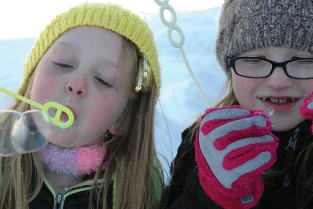 Kids blowing bubbles outside in the winte