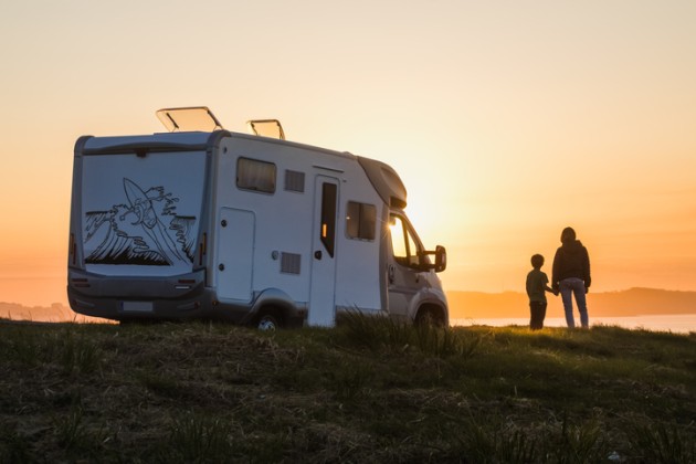 Recreational vehicle at sunset with parent and child holding hands in sillouette. 