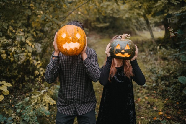 Two kids holding carved pumpkins up to their faces.