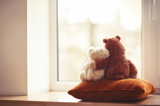 Two teddy bears hugging on a pillow. 