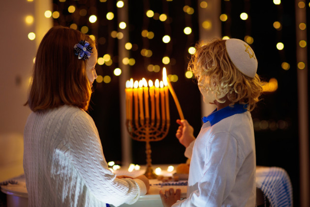 A boy and a girl lighting a menorah together.