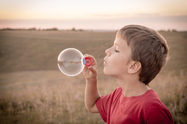 boy blowing soap bubbles on sepia toned landscape