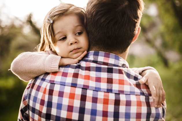 Little girl hugging a man wearing a plaid shirt.