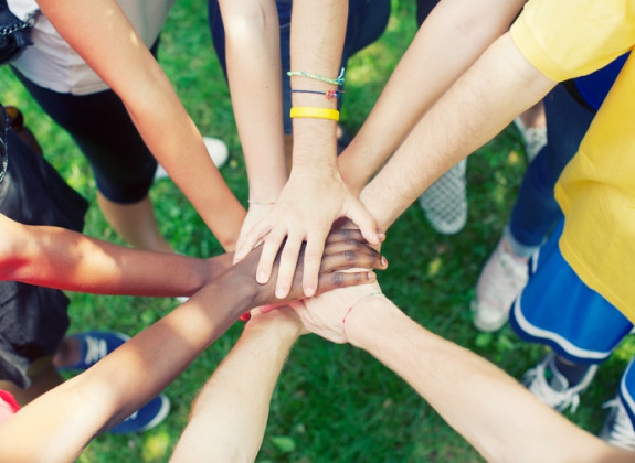 Multiracial children holding hands in a circle on grass.