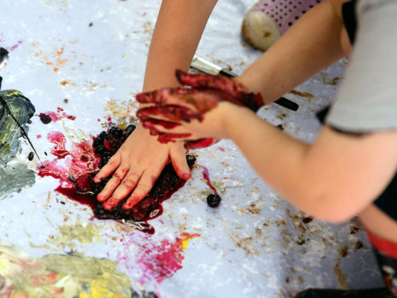 A child using their hands to make nature paint 