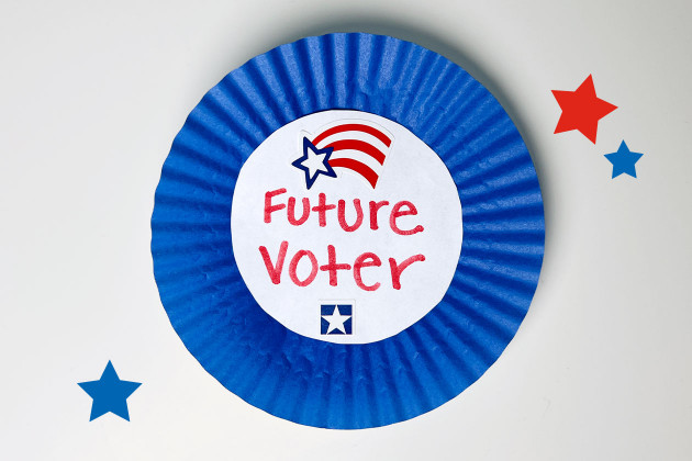The image shows a colorful craft with the words "Future Voter" prominently displayed. The design features bold red, white, and blue colors, arranged in a patriotic style. The text is centered in a paper cutouts to add a festive, child-friendly appeal, emphasizing the theme of civic engagement for young future voters.