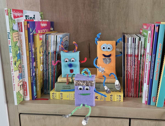 Three crafted robots sitting on a bookshelf.