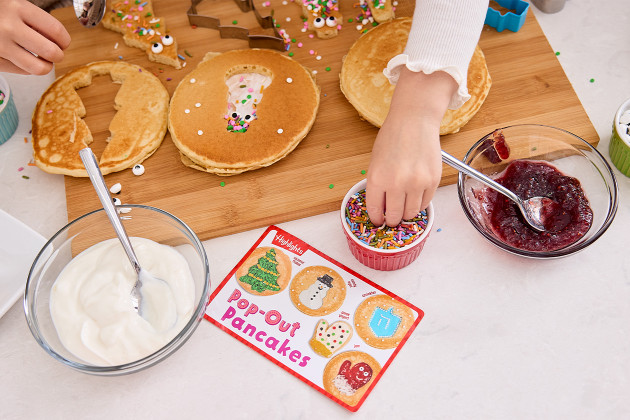 Kids decorate pancakes using a Pop-out Pancake Highlights recipe using colorful sprinkles and toppings, with yogurt, jam, as a fun family holiday tradition.