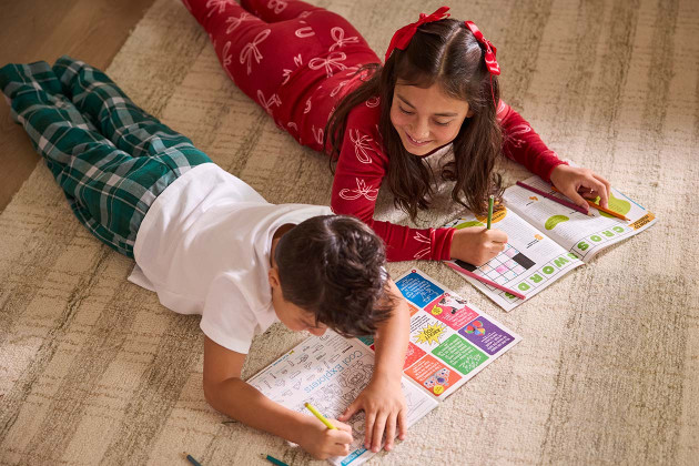 two kids laying on ground, completing puzzles from Highlights