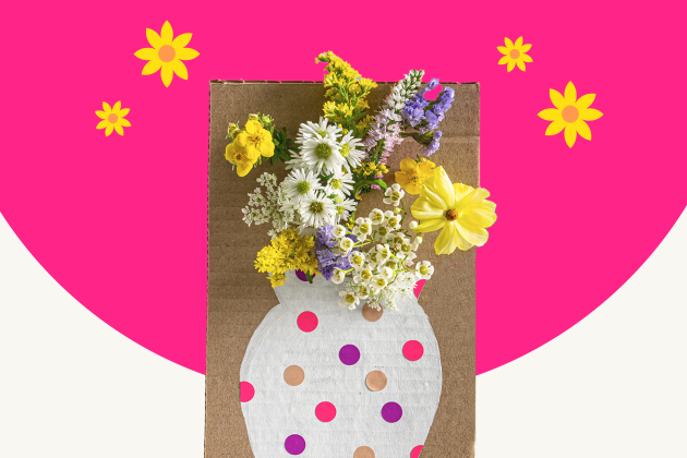 cardboard vase craft holding yellow flowers on pink and white background