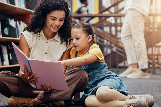 child reading on library floor with adult 