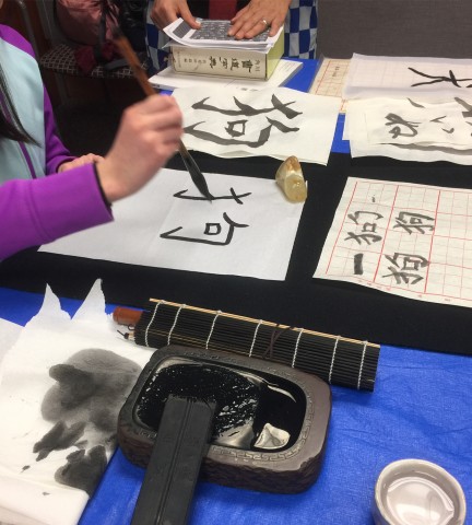 Traditional ink stone and papers with Chinese characters written on them.