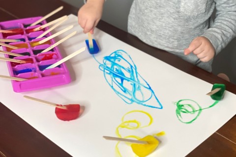 A child drawing with ice cube paints.