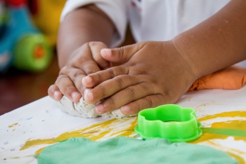 A pair of small hands molding play clay.