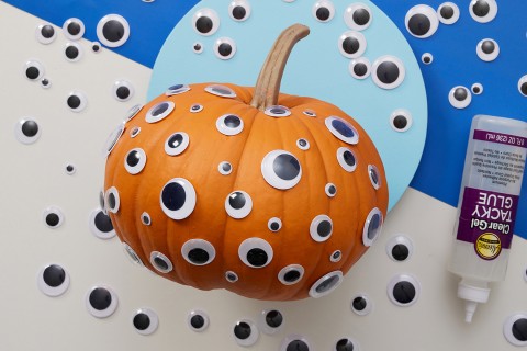 Big and small googly eyes glued all over a pumpkin.