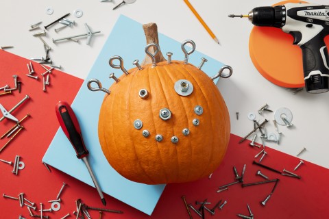 Nuts, screws and bolts arranged to make a pumpkin face.