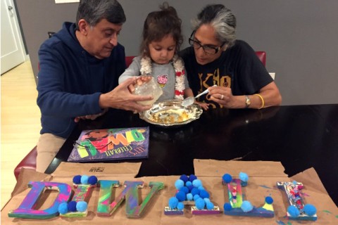 Grandparents doing a Diwali craft with their grandchild.