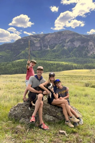 Shepherd family sitting on a rock near a mountain.