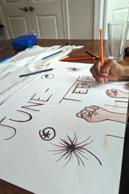 A girl draws a Juneteenth sign, celebrating Black independence.