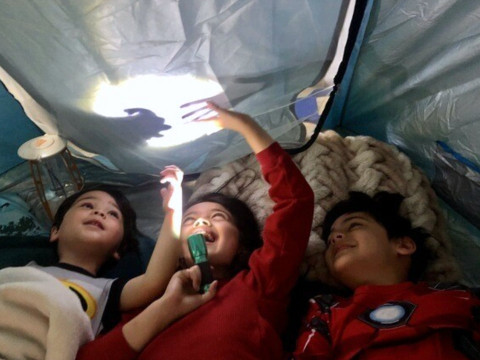 Kids playing with flashlights in a tent