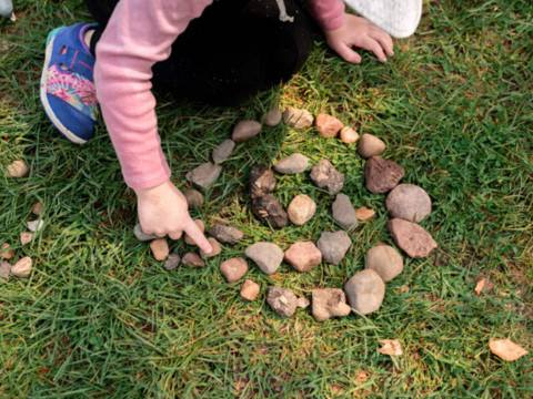 Child making a spiral out of rocks