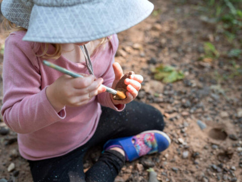 Child using a paintbrush to excavate rocks