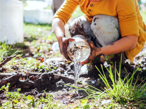 Child pouring water into the dirt