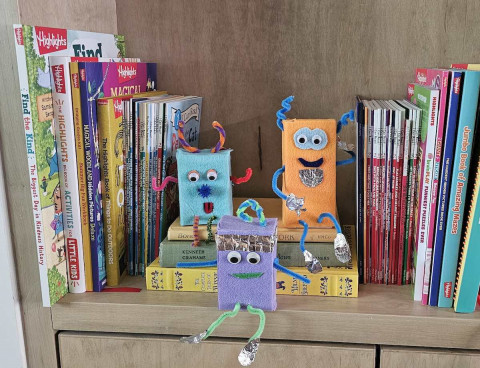 Three crafted robots sitting on a bookshelf.